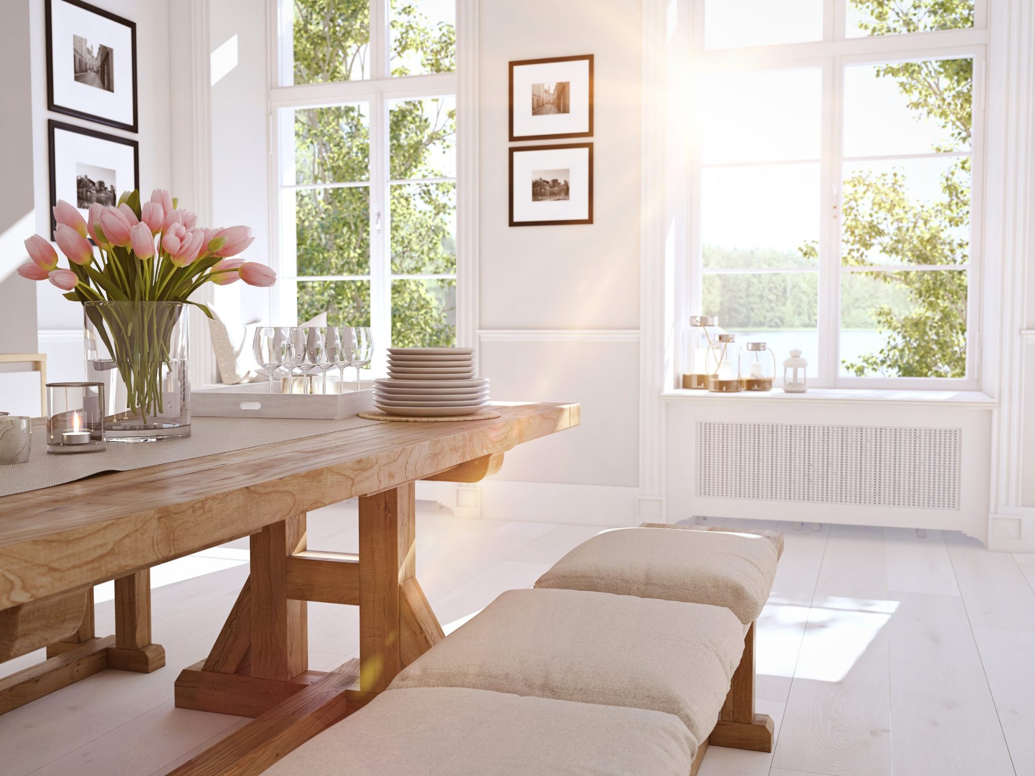 Bright dining room with wooden table, pink tulips, place settings, and garden views through large windows